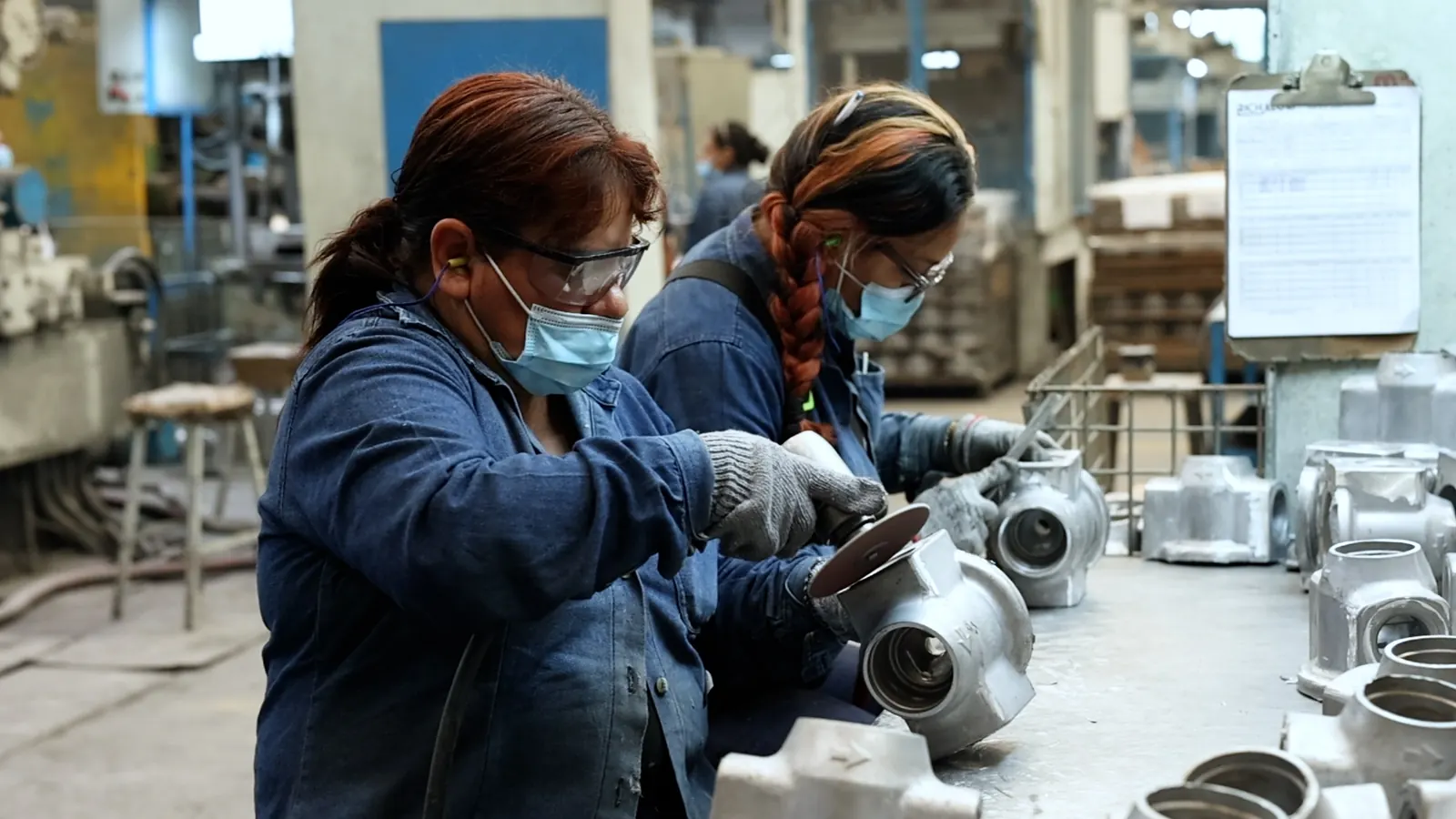 Workers grinding and finishing cast metal housings