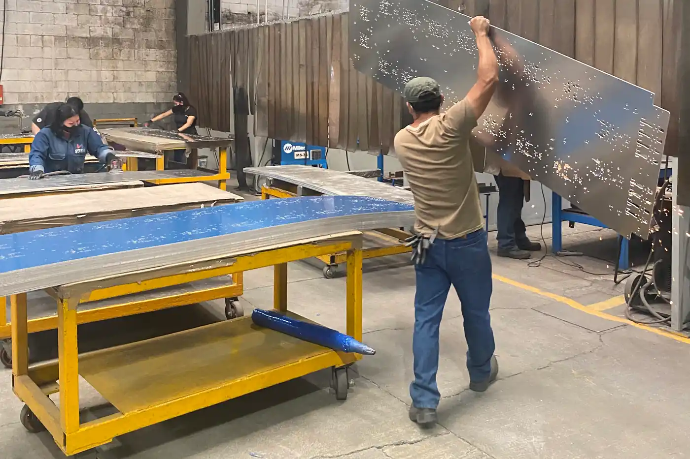 Fabricator lifting a profile-cut steel panel in Monterrey