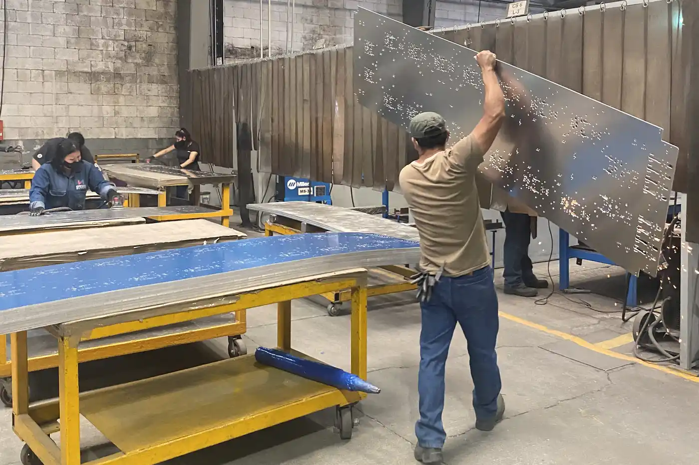 Fabricator lifting a profile-cut steel panel off the layout bench in Monterrey