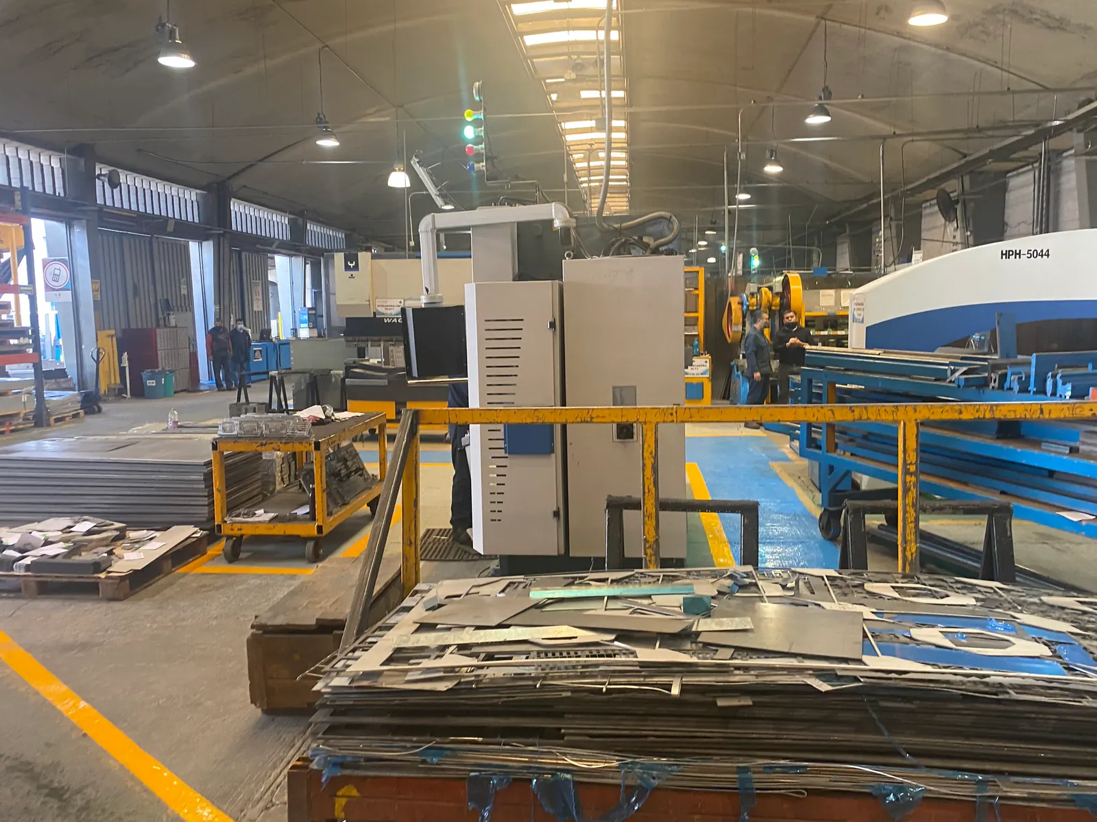 Sheet-metal shop floor with production equipment and cut metal panels